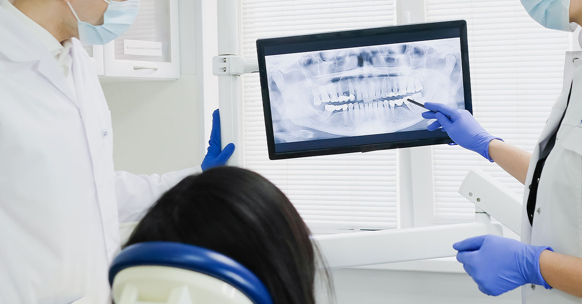 Dental xray being examined by the dentists and patient on a screen